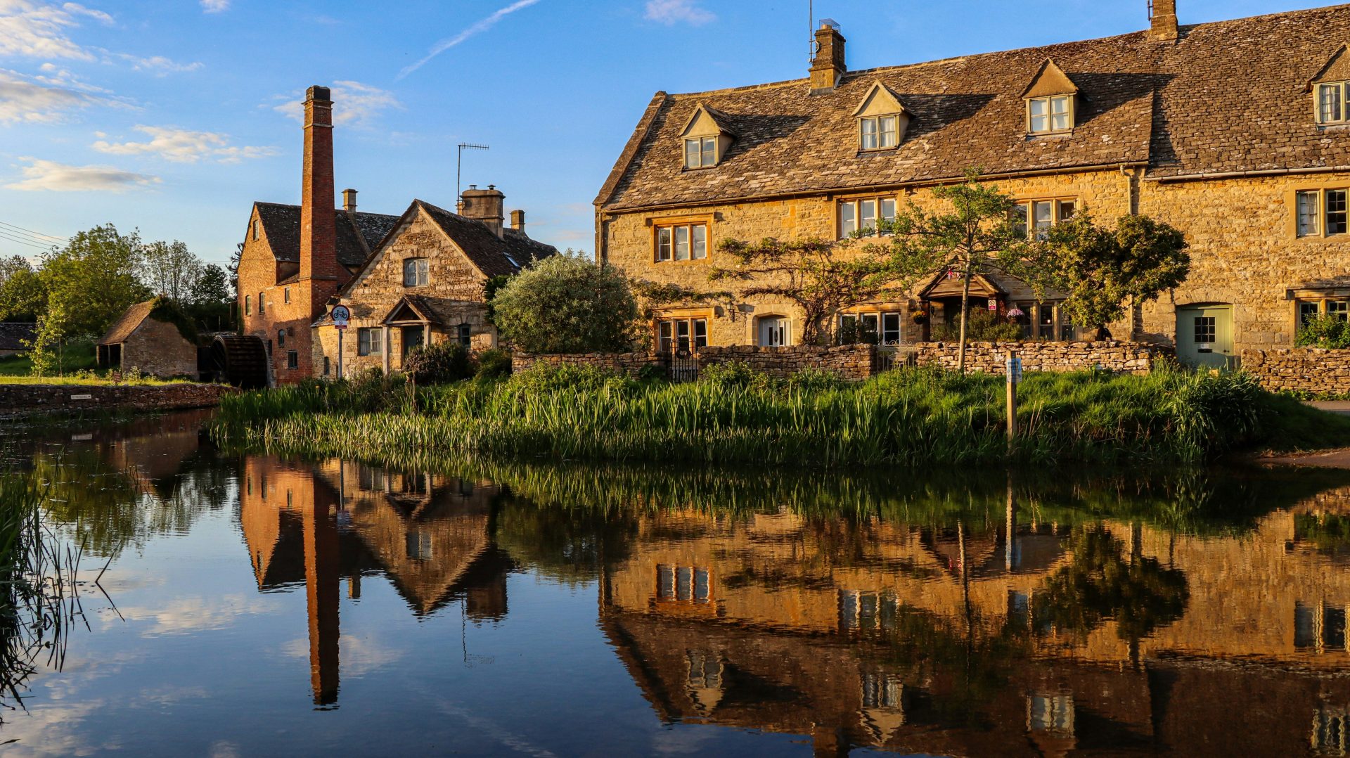 Old stone buildings and chimney reflected in still water